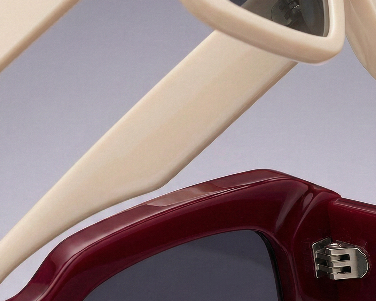 Dos pares de gafas de sol con montura rectangular: una crema con cristales oscuros y otra granate con detalle metálico
