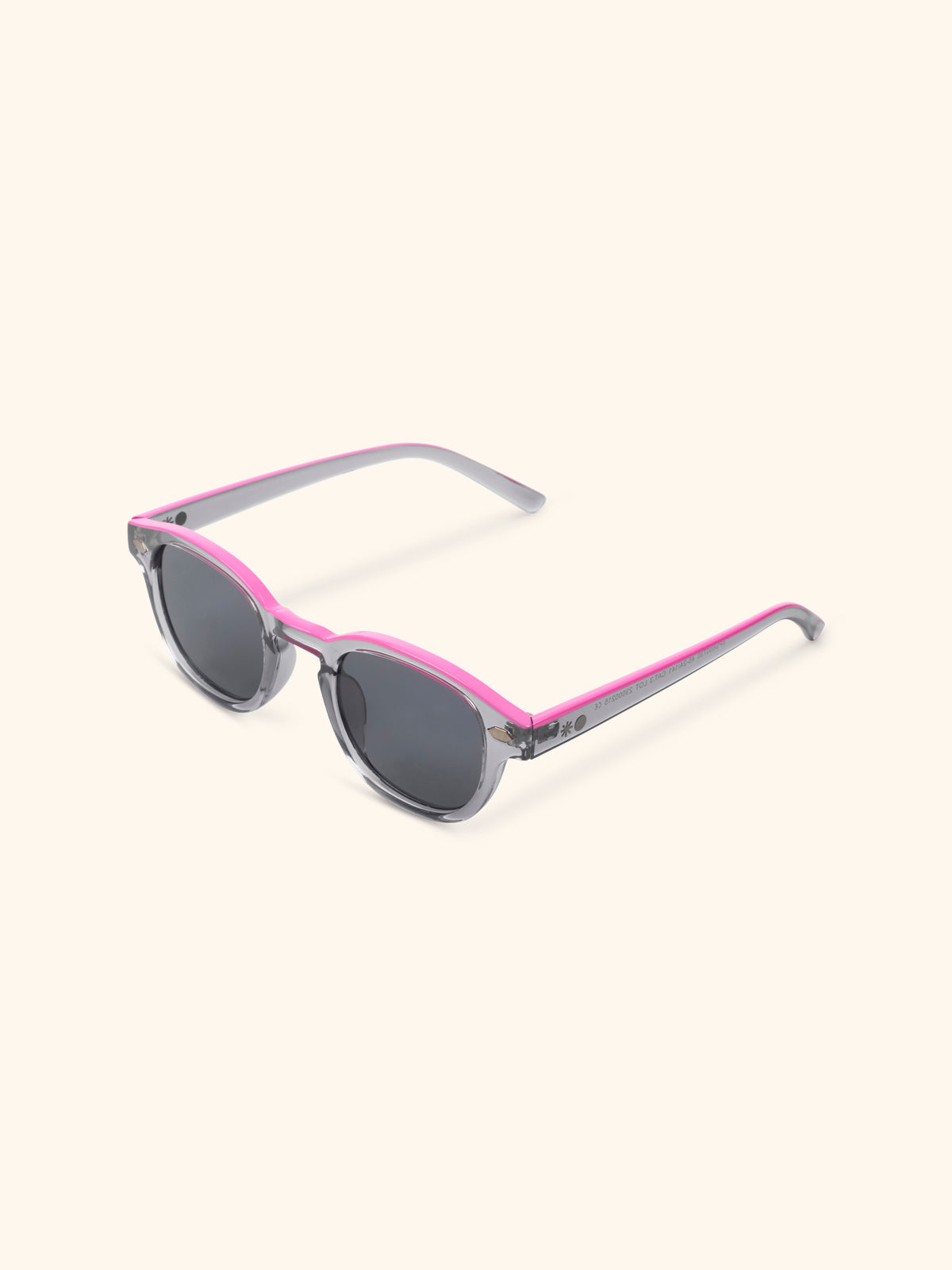 Gafas de sol con montura gris cristal y ribete rosa magenta, vista en perspectiva sobre fondo crema